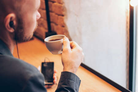 The man using mobile phone, sitting with coffee at cafeの写真素材