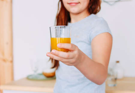 The girl holding glass of orange juice in hand, selective focusの写真素材