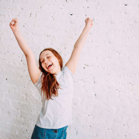 Happy teenager girl on the white background of the wall