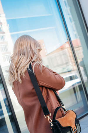 Stylish fashionable blonde woman wearing coat and sunglasses speaking on mobile phone at the streetの写真素材