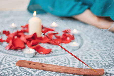 Burning incense red stick on candles background and woman practicing yoga