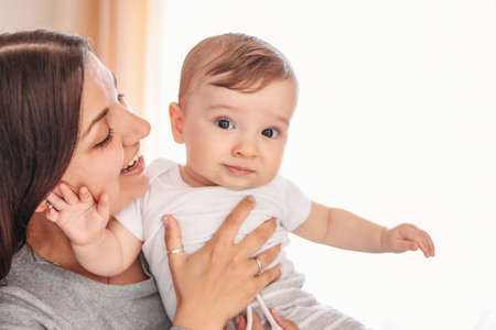 Charming little baby boy 6-8 months with mother at home, close up candid portrait