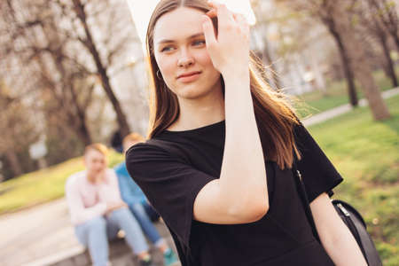 Young beautiful long hair girl on two boys friends background in city streetの写真素材