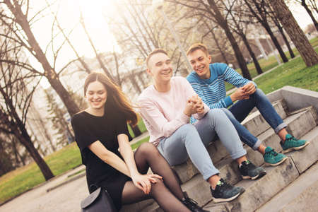 Group of friends Millennials students teenagers sitting at city street, friendship