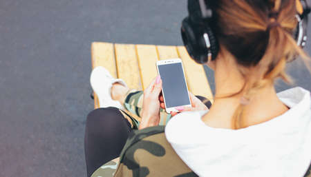Attractive fit young woman in headphones and military colored sport wear doing training with mobile on street workout area. The healthy lifestyle in cityの写真素材
