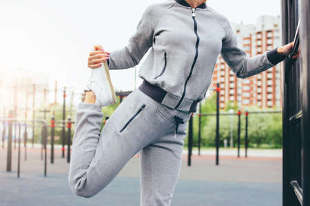 Attractive fit young woman in grey sport wear the doing warm up stretching before training on the street workout area. The healthy lifestyle in city conceptの写真素材