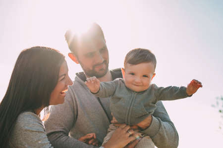 Happy family with cute baby boy on sky background outdoors, sensitivity to the nature conceptの写真素材