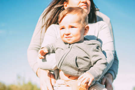 Cute baby boy with his family on sky background outdoors, sensitivity to the nature conceptの写真素材