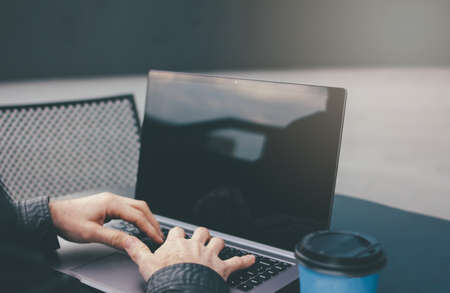 Adult successful man with laptop in the street cafe with paper cup of coffee