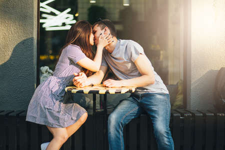 Happy young couple in love teenagers friends dressed in casual style kissing in the street cafeの写真素材