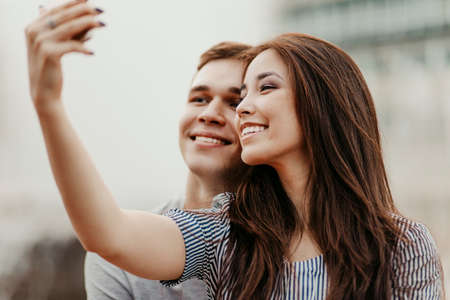 Happy young couple in love teenagers friends dressed in casual style making selfie at the streetの写真素材