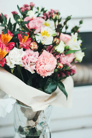 Beautiful bouquet of different flowers in craft paper and glass vaseの写真素材