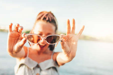Close up portrait happy carefree young woman with african braids in sunglasses enjoy life on the beach, summer vacation timeの写真素材