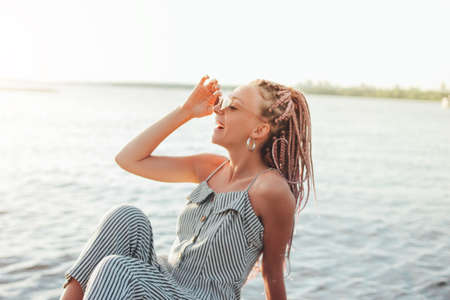 Happy carefree young woman with african braids in sunglasses enjoy life on the beach, summer vacation timeの写真素材