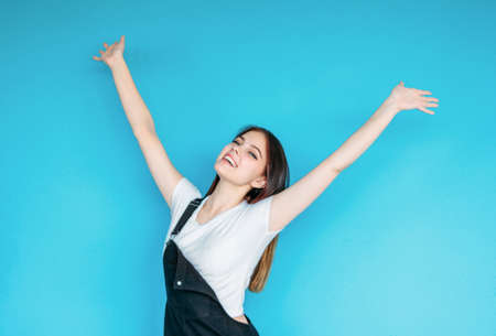 Happy carefree girl with dark long hair in white t-shirt isolated on the blue backgroundの写真素材