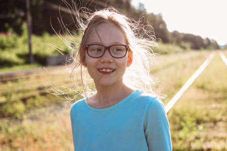 Portrait of charming smiling girl in glasses on the background of railway, summer time in country sideの写真素材