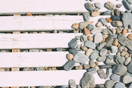 Background of pebbles stones on white wooden boards on the beachの写真素材