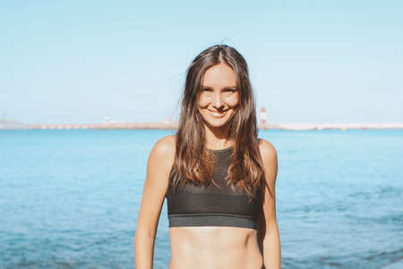 Young slim athletic long hair smiling woman in the sportswear on the sea beach, healthy lifestyle