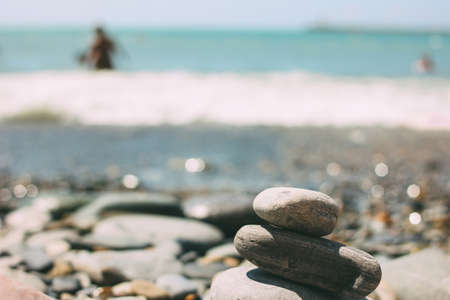 Pile of pebbles stones on the blurred sea beach backgroundの写真素材