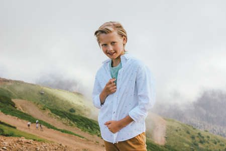 Blonde smiling boy looking at camera on background of wonderful view of the mountain resort, family travel adventure lifestyleの写真素材