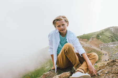 Blonde smiling boy looking at camera on background of wonderful view of the mountain resort, family travel adventure lifestyleの写真素材