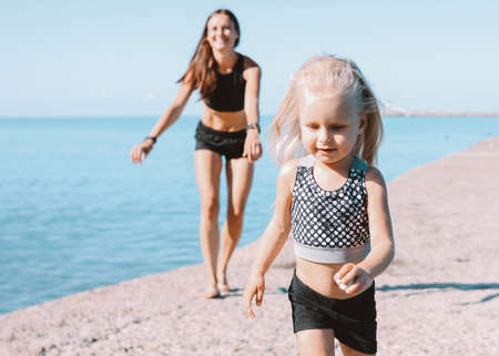 Little cute girl looking to the fit mom on beach, healthy lifestyle, sport familyの写真素材