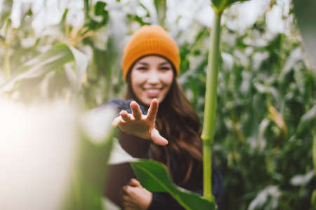 Beautiful carefree long hair asian girl in the yellow hat and knitted sweater in autumn corn field. Sensitivity to nature conceptの写真素材