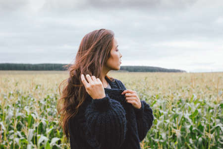 Beautiful carefree long hair asian girl in knitted sweater in the autumn corn field. Sensitivity to nature conceptの写真素材