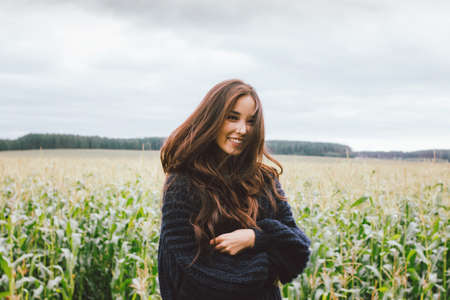 Beautiful carefree long hair asian girl in knitted sweater in the autumn corn field. Sensitivity to nature conceptの写真素材