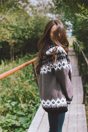 Beautiful carefree long hair asian girl in knitted nordic sweater in the autumn nature parkの写真素材