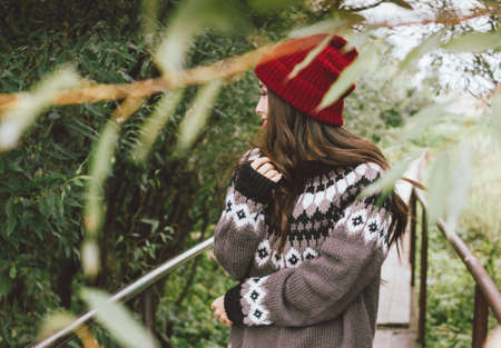 Beautiful carefree long hair asian girl in red hat and knitted nordic sweater in autumn nature park, travel adventure lifestyleの写真素材
