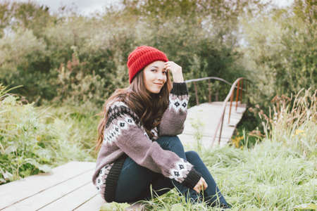 Beautiful carefree long hair asian girl in the red hat and knitted nordic sweater in autumn nature park, travel adventure lifestyleの写真素材