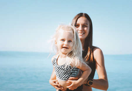 Young fit woman mom with little cute girl exercising on the beach together, healthy lifestyleの写真素材