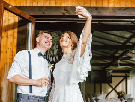 Happy newly married couple, smiling bride brunette young woman with boho style bouquet with groom, close up portrait outdoorsの写真素材