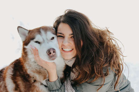 Red dog husky with his mistress brunette girl in the forest outdoors in the cold season