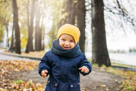 Cute happy baby boy in fashionable casual clothes in the autumn nature park