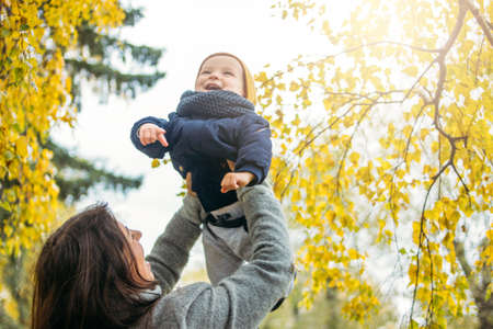 Portrait of happy mother with baby boy in the autumn park