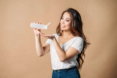 Beauty portrait of young asian woman with beautiful long healthy hair with care product jar on the beige backgroundの写真素材
