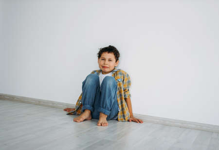 Frustrated Moody tween boy sitting on the floor near wall at homeの写真素材
