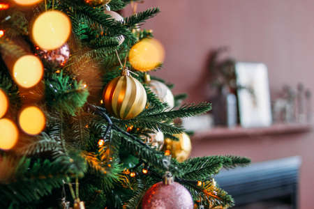 Decorated Christmas tree in gold and purple toys with lights bokeh textured background