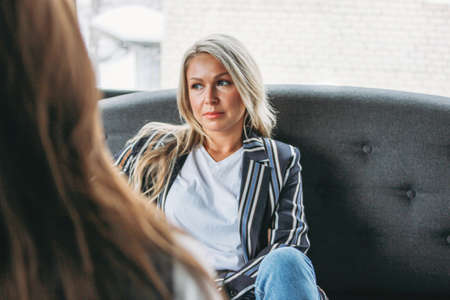 Upset young woman in the office of psychotherapist or doctor, women communicate to each other