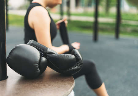 Black leather boxing gloves on background of athletic girl shakes boxing bandages on hands before trainingの写真素材