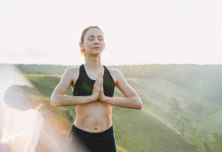Young woman girl practice yoga looking on the beautiful landscape on early morning. Local tourism, weekend tripの写真素材