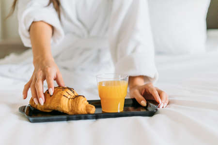 Beautiful young asian woman with long hair in white robe using mobile having breakfast  and orange...