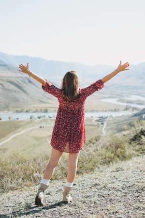 Young brunette woman in red dress on background of turquoise Katun river, Altai mountainsの写真素材