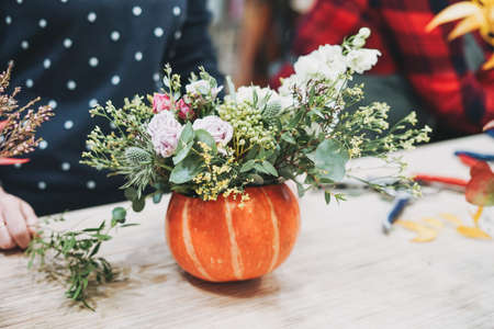 DIY autumn flower arrangement bouquet in pumpkin, florist at work, floristry studio