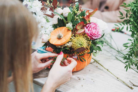 DIY autumn flower arrangement bouquet in pumpkin, florist at work, floristry studioの写真素材