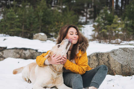 Young brunette beautiful woman in hat and gray poncho in the winter forestの写真素材