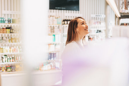 Adult pretty smiling woman with dark hair in cosmetics and perfume store, holiday shoppingの写真素材
