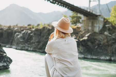Young woman in felt hat from behind looking on Horochowski bridge on Katun river, Altai mountainsの写真素材